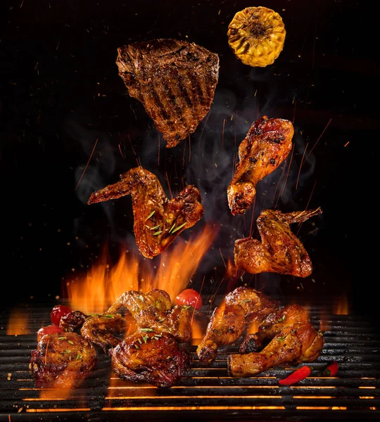 Hühnerkeulen und -flügel auf dem Grill mit Flammen — Stockfoto