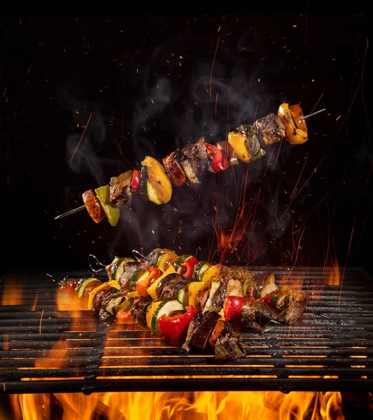 Tasty skewers on the grill with flames — Stock Photo, Image