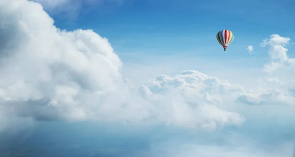 Colorful hot air balloon flying against blue cloudy sky. — Stock Photo, Image