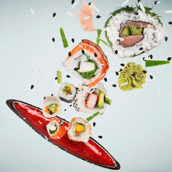 Kousky lahodného japonského sushi zamrzlé ve vzduchu. — Stock fotografie