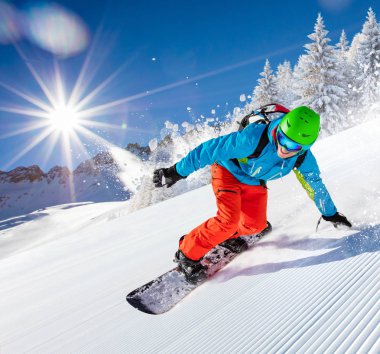 Etkin adam snowboard yamaçta güzel güneşli gün boyunca ountains içinde sürme..