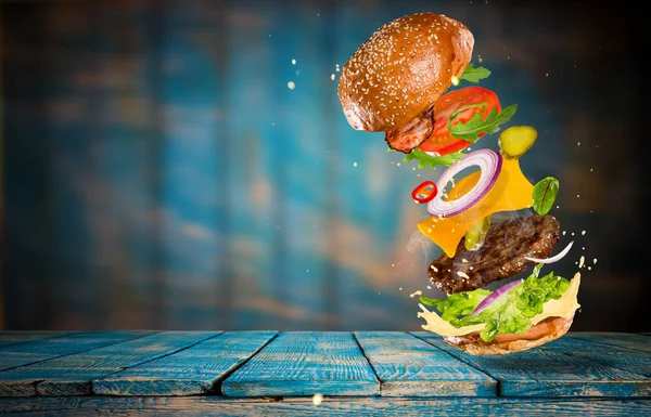 Big gustoso hamburger con ingredienti volanti . — Foto Stock