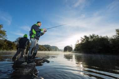 Erkekler nehir sinek çubuk ile yaz sabahı sırasında Balık tutma. Güzel sis.