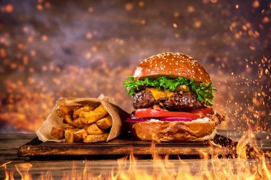 Ev yapımı lezzetli burger patates kızartması ve yangın alevleri Close-up.