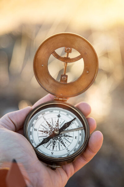 Вид от первого лица на руку человека с ретро-аналоговым компасом, высокогорный пейзаж
.