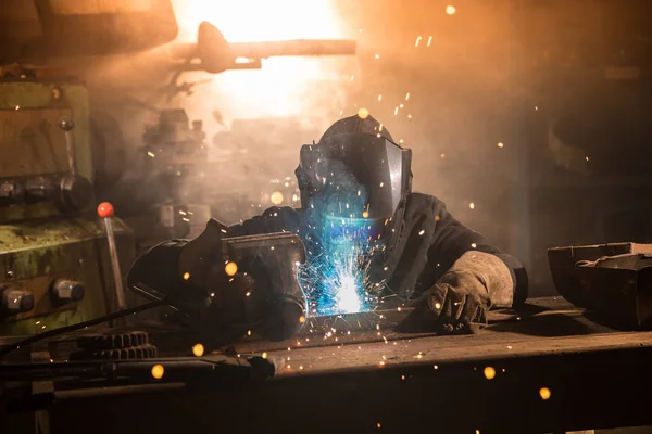 Сварщик готовит металлическую деталь на заводе — стоковое фото