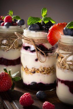 Müsli, taze meyveler ve ahşap masa üzerinde reçel lezzetli yoğurt.