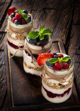 Müsli, taze meyveler ve ahşap masa üzerinde reçel lezzetli yoğurt.