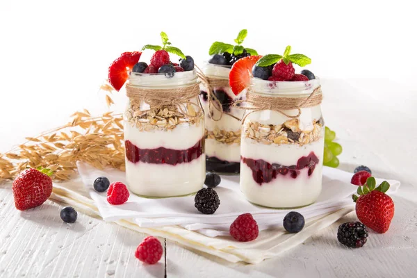 Yaourts savoureux au muesli, baies fraîches et confiture sur table en bois . — Photo