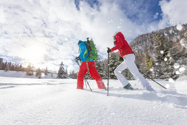 Sneeuwschoen wandelaars uitgevoerd in poeder sneeuw met prachtige zonsopgang licht. — Stockfoto