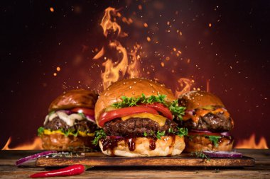 Tasty burger with french fries and fire. clipart