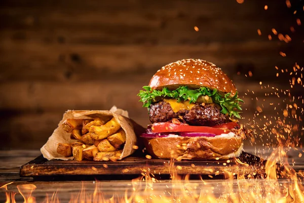 Hambúrguer saboroso com batatas fritas e fogo . — Fotografia de Stock