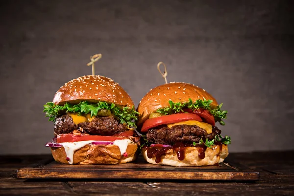 Smaczne hamburgery na drewnianym stole. — Zdjęcie stockowe