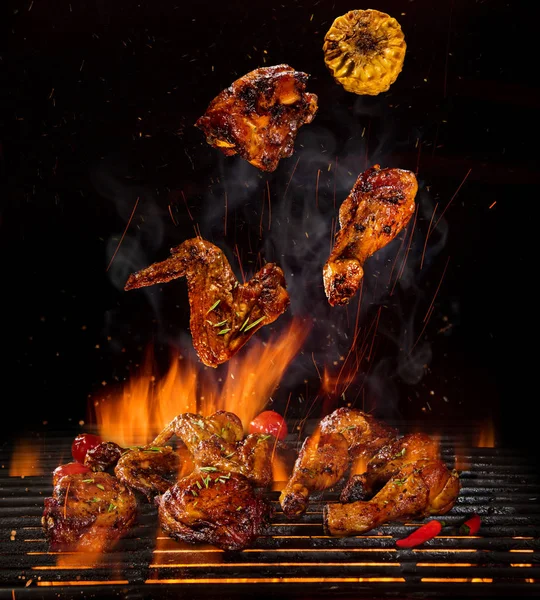 Hühnerkeulen und -flügel auf dem Grill mit Flammen — Stockfoto