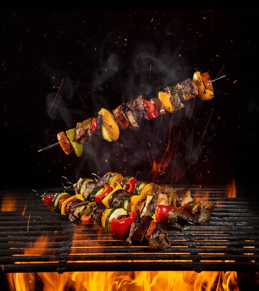 Tasty skewers on the grill with flames — Stock Photo, Image