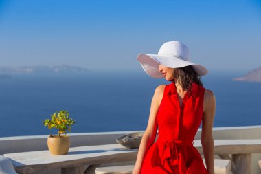 Santorini seyahat ediyor. Kırmızı elbiseli esmer kadın ünlü beyaz Oia köyünü ziyaret ediyor..