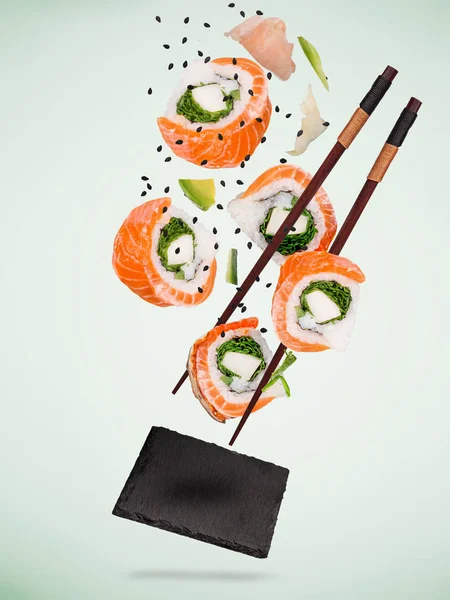 Pedaços de delicioso sushi japonês congelado no ar. — Fotografia de Stock