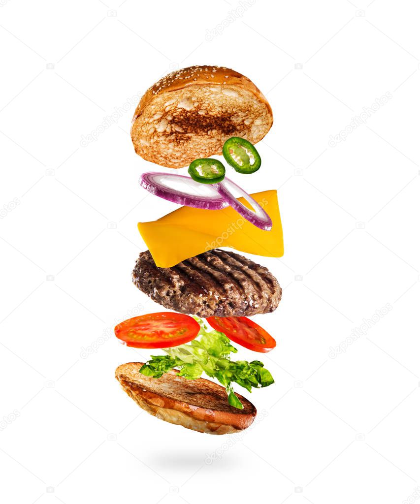 Tasty hamburger with flying ingredients on white background