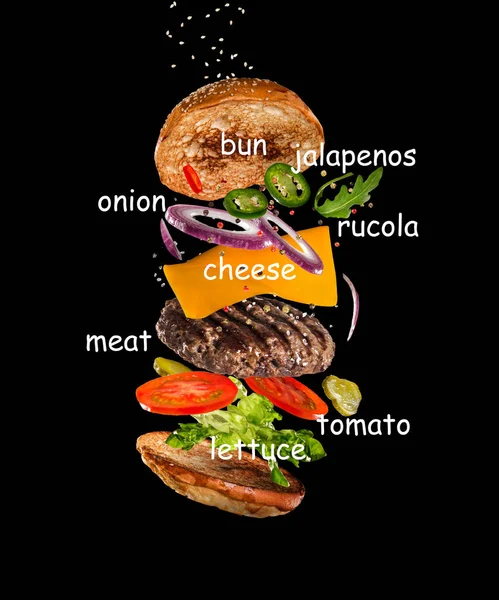 Chutný hamburger s létáním ingredience na tmavém pozadí — Stock fotografie