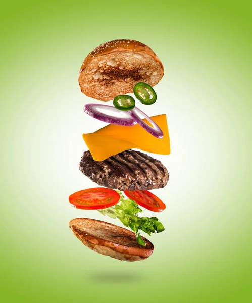 Смачний чізбургер з літаючими інгредієнтами на кольоровому пастельному фоні — стокове фото