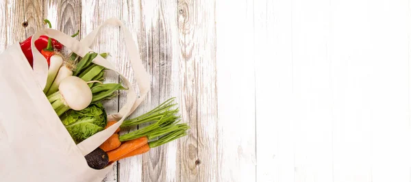 Légumes frais dans des sacs en coton bio sur une vieille table en bois . — Photo