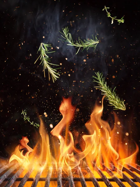 Rosemary flying above cast iron grate with fire flames. — Stock Photo, Image