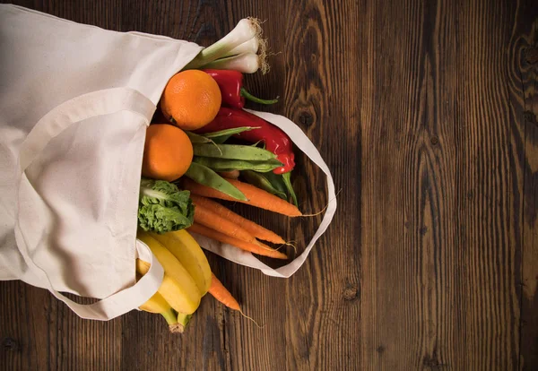 Sayuran segar dalam tas kapas bio eco di atas meja kayu tua. Konsep zero waste shopping . — Stok Foto