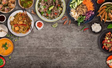 Köy taşından arka planda çeşitli malzemeler içeren Asya yemekleri, üst görünüm.