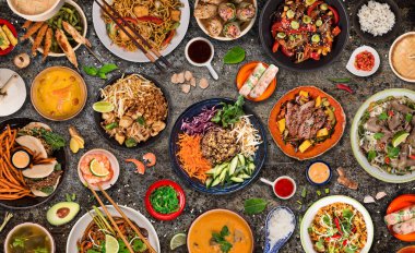Köy taşından arka planda çeşitli malzemeler içeren Asya yemekleri, üst görünüm.