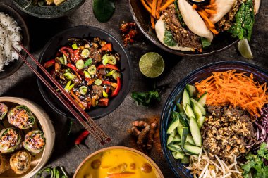 Köy taşından arka planda çeşitli malzemeler içeren Asya yemekleri, üst görünüm.