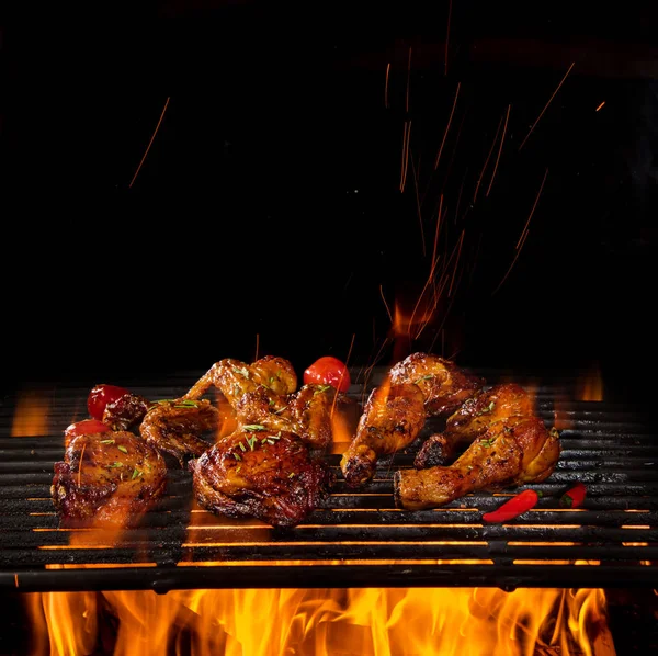 Hühnerkeulen und -flügel auf dem Grill mit Flammen — Stockfoto