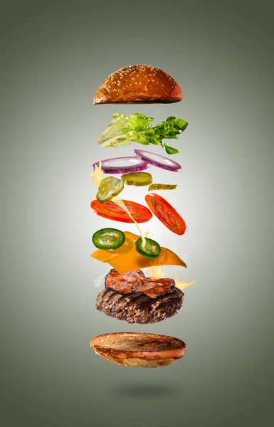 Tasty cheeseburger with flying ingredients on color pastel background