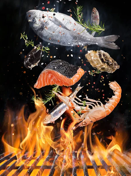 Kettle grill with fire flames, cast iron grate and tasty sea fishes flying in the air. — Stock Photo, Image