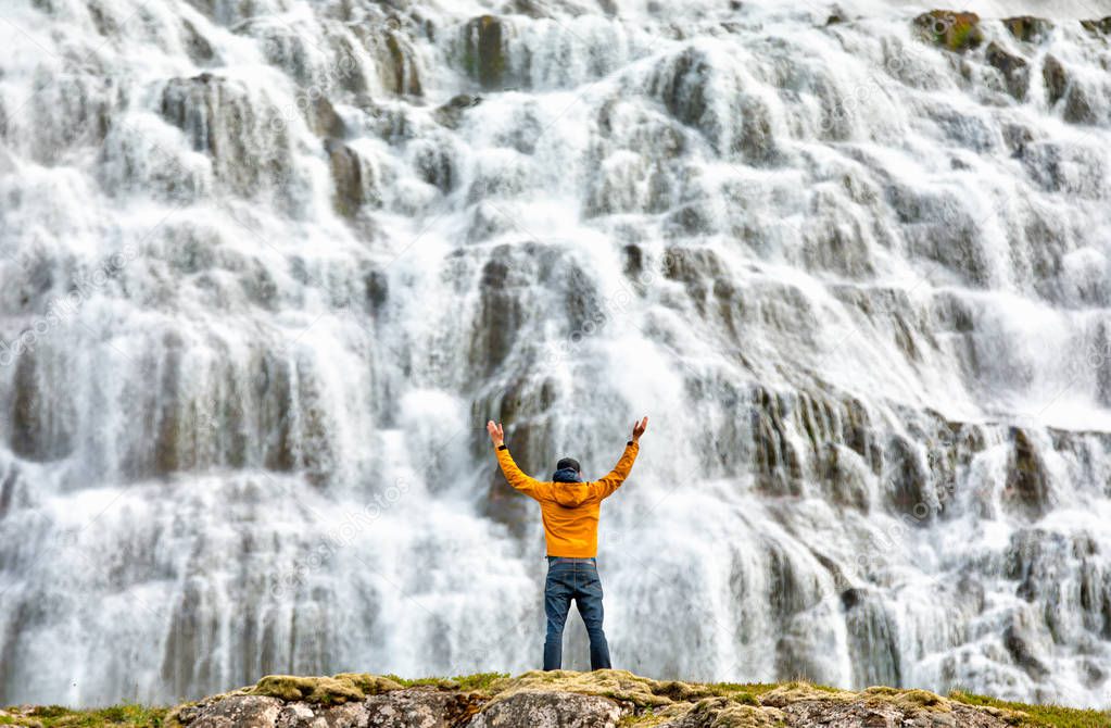 Man standing by beautiful cascades of famlus Dynjandi waterfall, Westfjords, Iceland