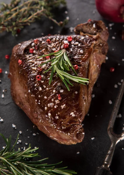 Steak z grilovaného hovězího masa na černém kamenném stole. Pohled shora. — Stock fotografie