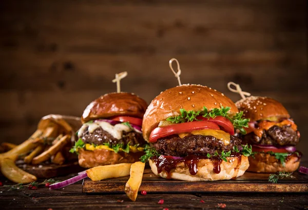 Sabrosas hamburguesas sobre mesa de madera. — Foto de Stock