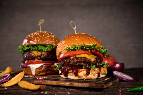 Chutné hamburgery na dřevěném stole. — Stock fotografie