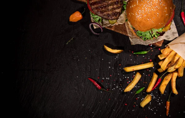 Siyah taş masada lezzetli burger üst görünümü. — Stok fotoğraf