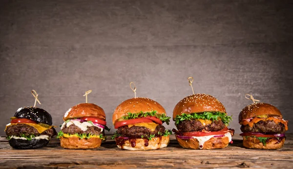 Sabrosas hamburguesas sobre mesa de madera. — Foto de Stock