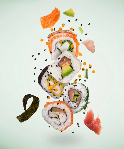 Trozos de delicioso sushi japonés congelado en el aire. — Foto de Stock