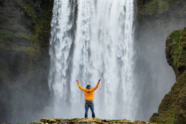 İzlanda 'daki ikonik Skogafoss şelalesinin güzelliğine hayran olan bir adam.