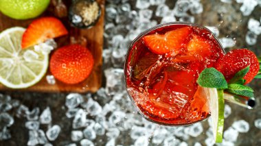 Taze çilekli mojito kokteylinin üst görüntüsü taze limon ve siyah taş zemin üzerinde nane yaprağı.