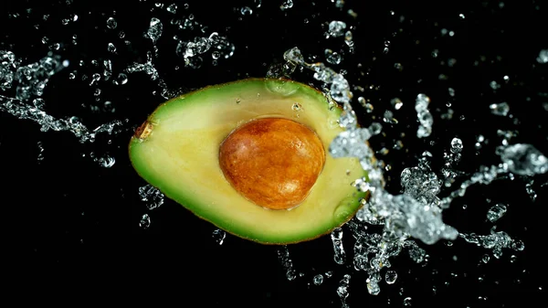 Freeze motion of sliced avocado with splashing water — Stock Photo, Image