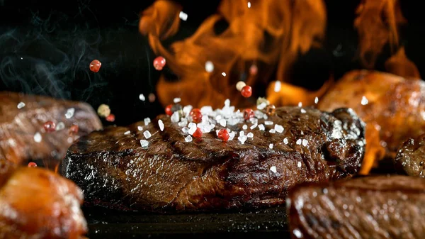 Chutné hovězí steak na litinové roštu s ohněm plameny. — Stock fotografie