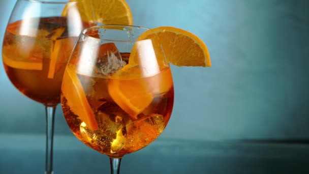 Cubo de hielo cayendo en un vaso de cóctel naranja. — Vídeos de Stock