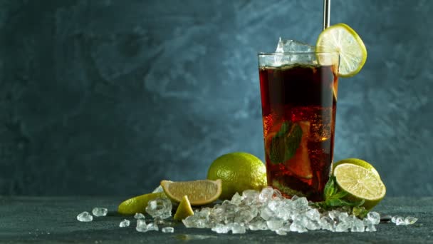 Verfrissende Cuba Libre cocktail in een glas op zwarte stenen tafel, macro slow motion shot. — Stockvideo