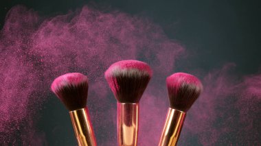 Makyaj fırçaları koyu arkaplanda birbirine dokunur