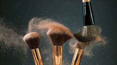 Makyaj fırçaları koyu arkaplanda birbirine dokunur