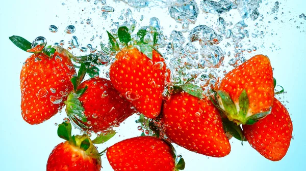 Prise de vue au gel de fraises fraîches tombant dans l'eau — Photo