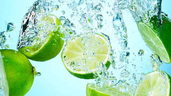 Freeze Motion Shot of Fresh Limes falling into water — Stock Photo, Image